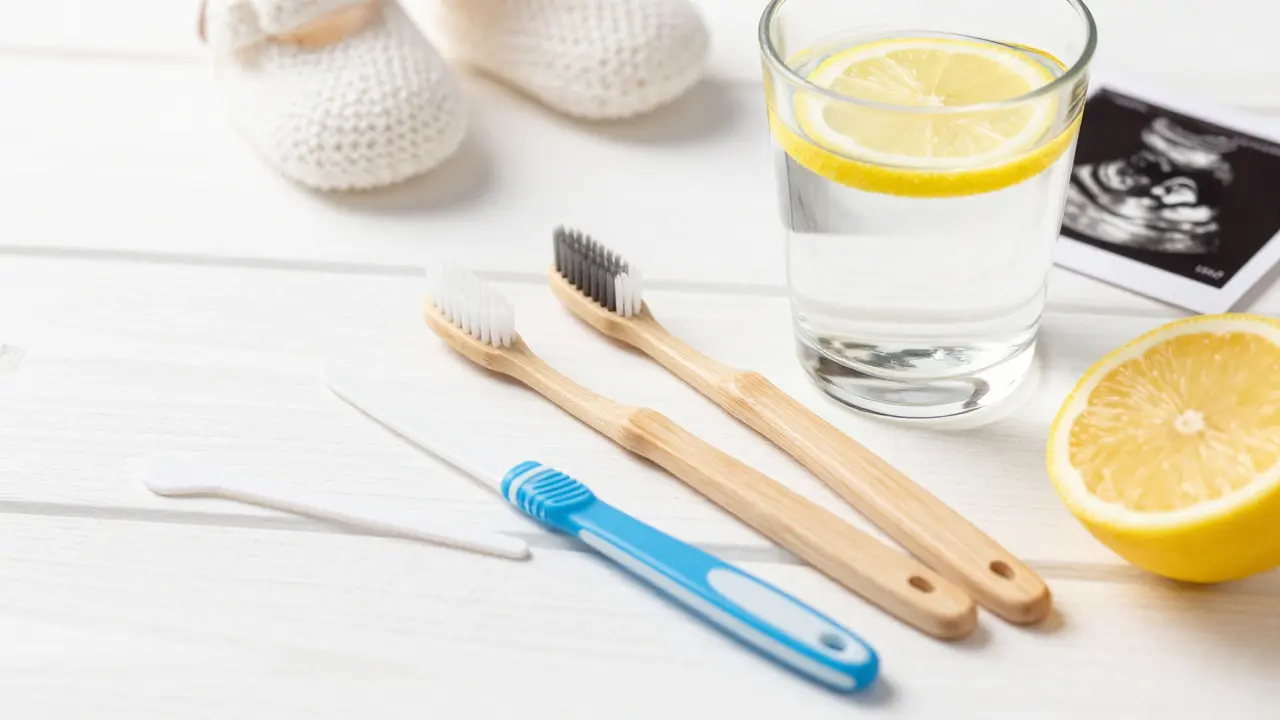 Sada pomůcek pro dentální hygienu vedle dětské botšky na bílém stole.